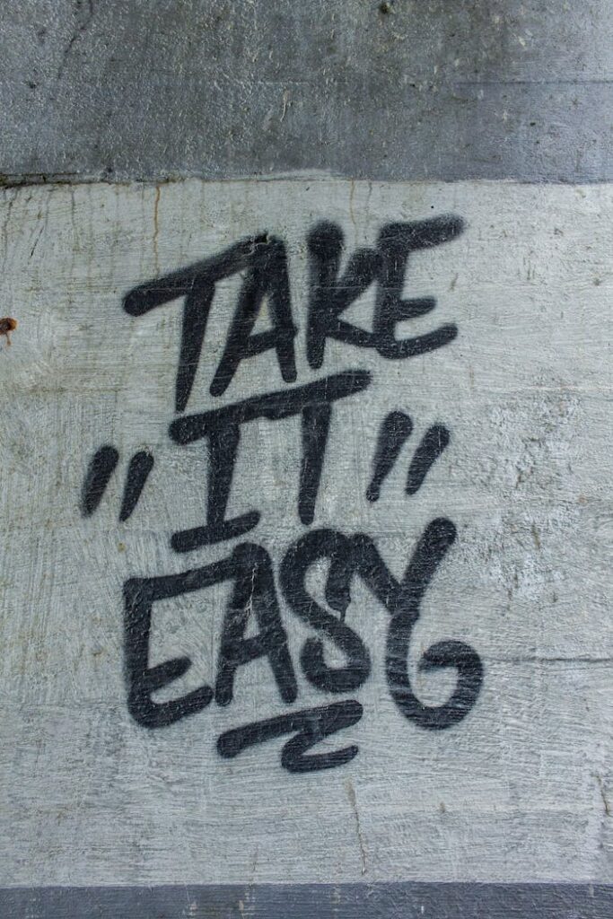 Black graffiti text 'Take it Easy' on a textured concrete wall.
